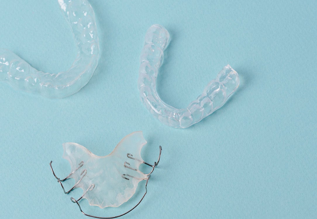 Stock image of two clear aligners and one metal retainer